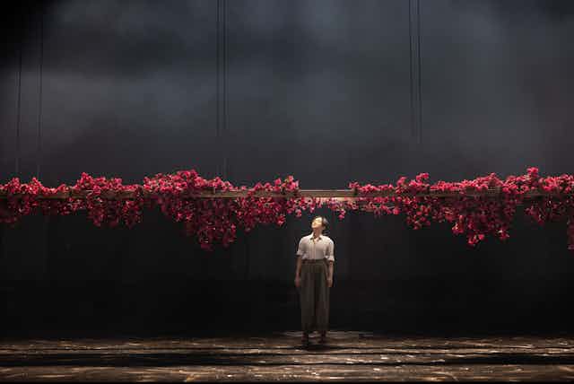 Production image: a woman looks up at a glut of roses
