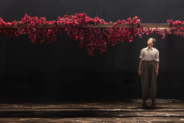 Production image: a woman looks up at a glut of roses