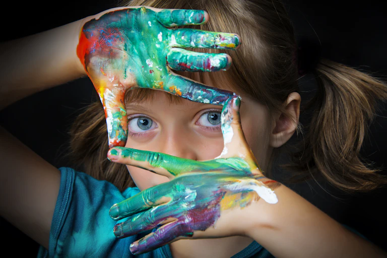 Petite fille après un cours de dessin avec des traces de peinture sur les mains