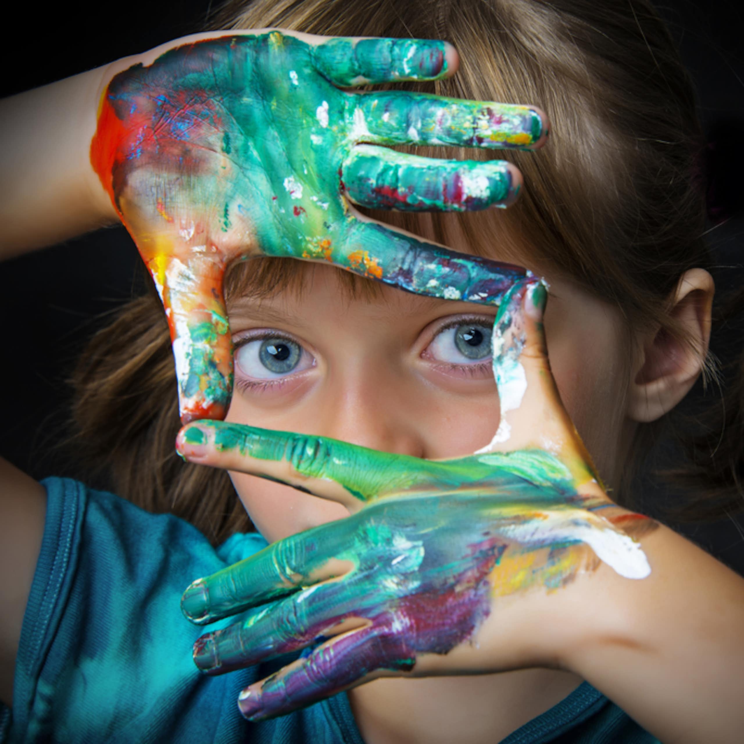 Petite fille après un cours de dessin avec des traces de peinture sur les mains