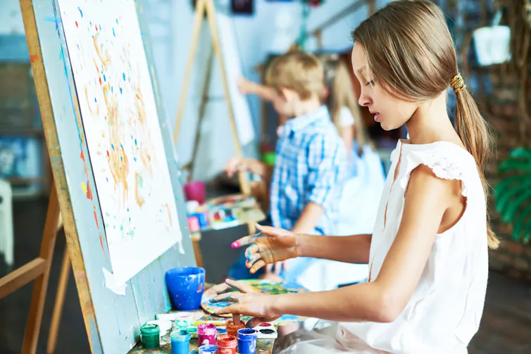 Enfants en train de faire de la peinture, assis face à des chevalets