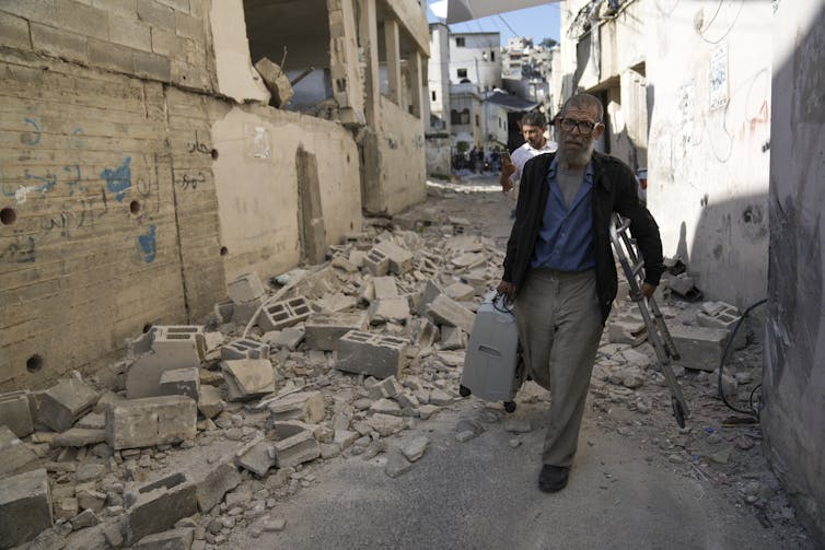 A man walks passed rubble of a damaged building.