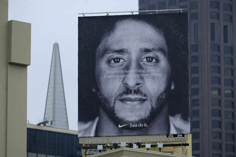A large billboard featuring a quote that says 'Believe in something, even if it means sacrificing everything' superimposed over a black-and-white portrait of a Black man
