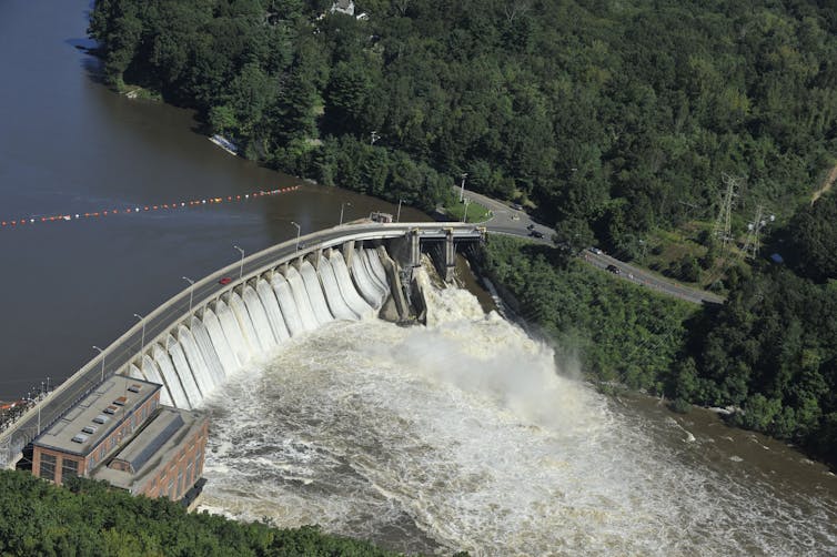 A large dam with every gate open, including a spill way.