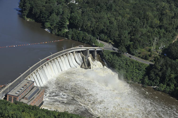 A large dam with every gate open, including a spill way.