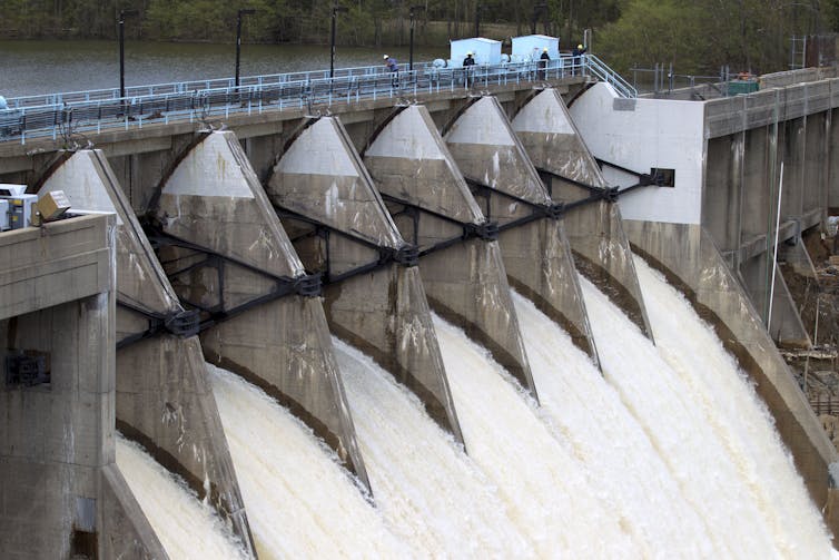 Water pours out of seven large flood gates of a dam.