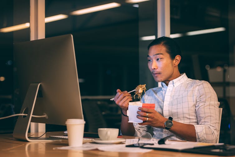 Man eats noodles at his desk