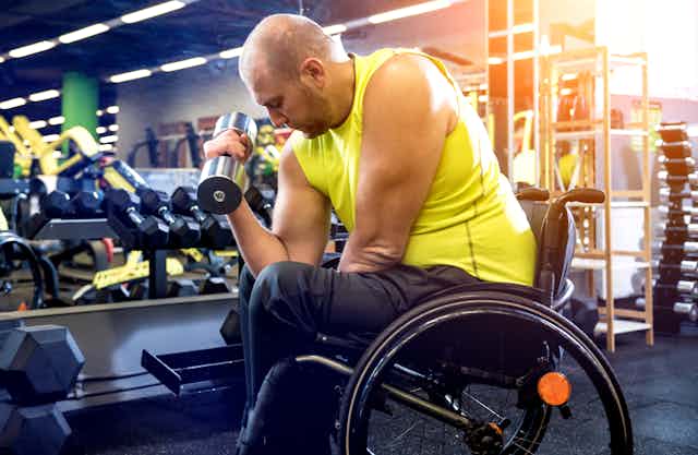 Hombre en silla de ruedas ejercitándose con pesas