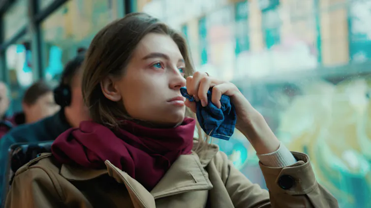 Woman sits on a train holding a tissue