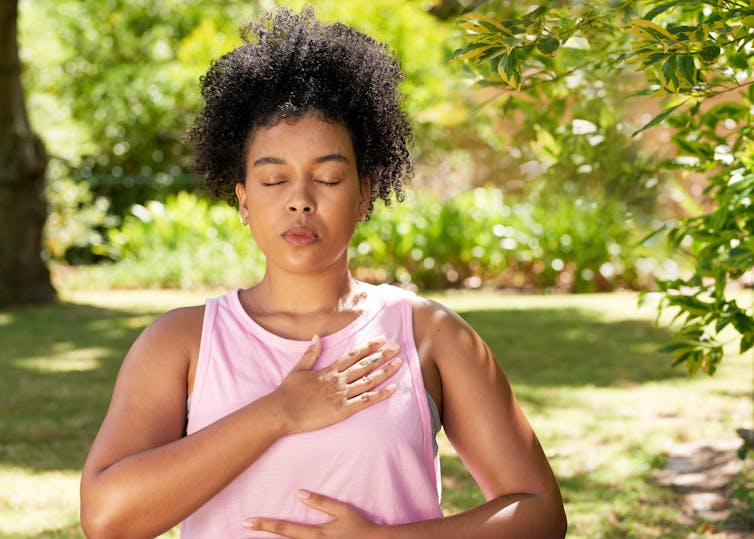 woman takes deep breaths outside. Hand on chest