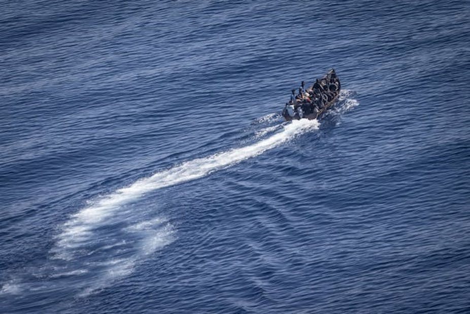 Un petit bateau de migrants sur fond de mer bleue en Méditerranée. 