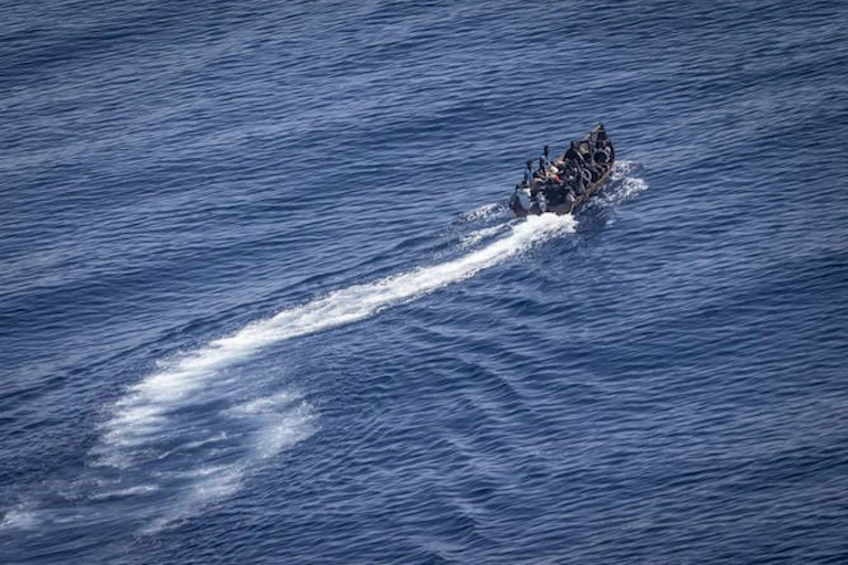 Un petit bateau de migrants sur fond de mer bleue en Méditerranée.