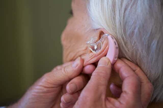 Older woman having hearing aid adjusted
