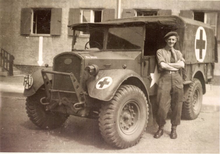 Ambulance driver stands in front of his vehicle