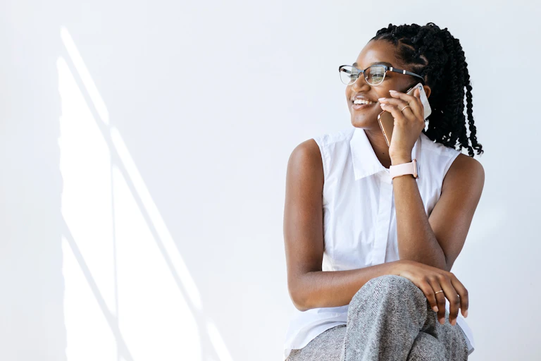Una mujer negra habla por teléfono sonriendo.