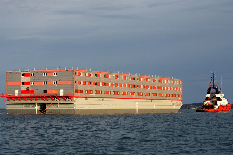 A tug boat pulls a large barge.