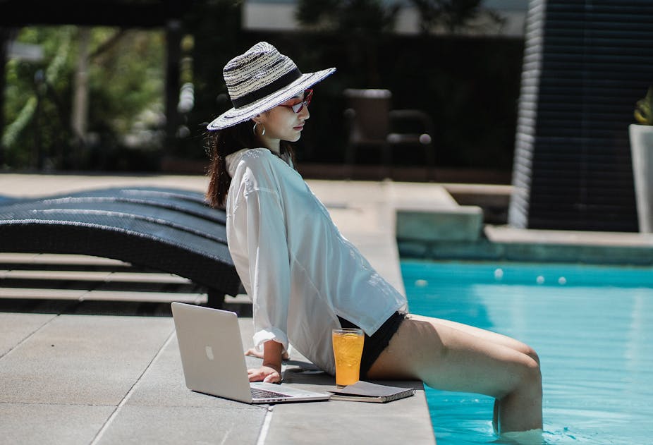 Jeune femme avec son ordinateur au bord de la piscine