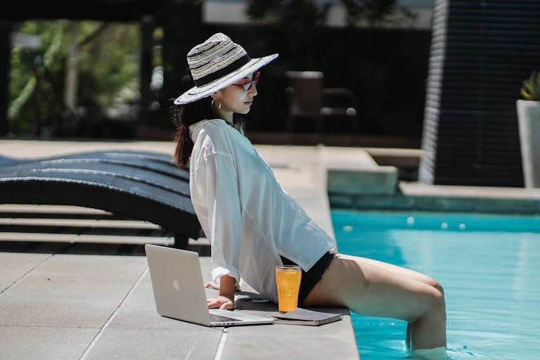 Jeune femme avec son ordinateur au bord de la piscine