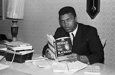 Muhammad Ali sits in his home and reads the book 'Message to the Blackman.'