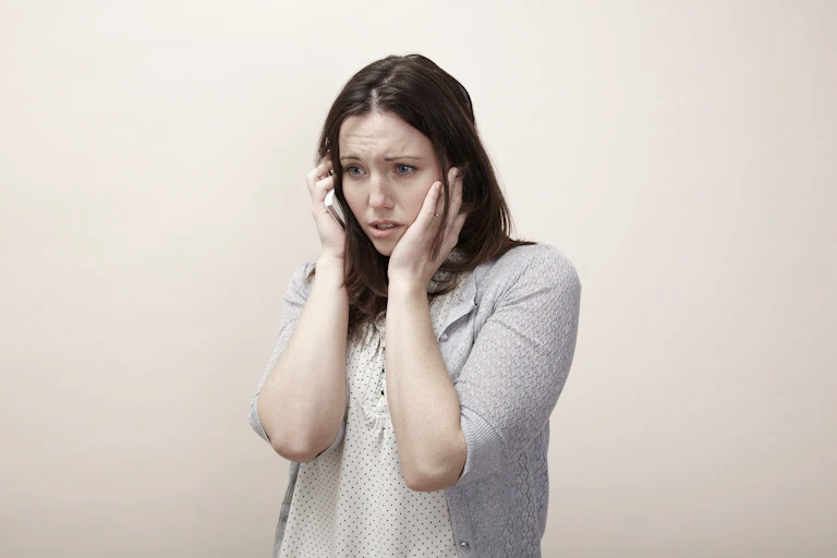 A distraught young woman is on the phone.