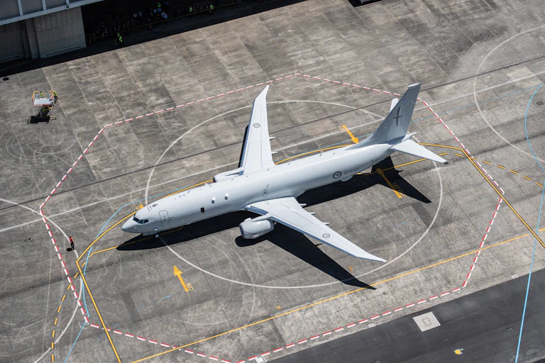 Military plane on tarmac outside hangar
