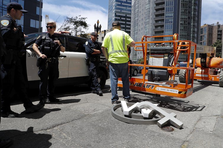 Turuncu yükseltilmiş bir çalışma platformunun önündeki kaldırımda bir @ işareti, bir w ve bir t yatıyor