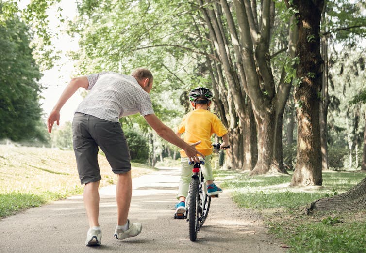 adult man helps child with bike