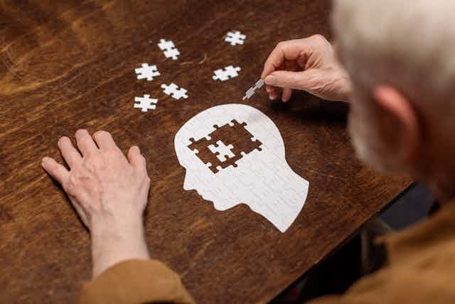A man putting together a puzzle of a head.