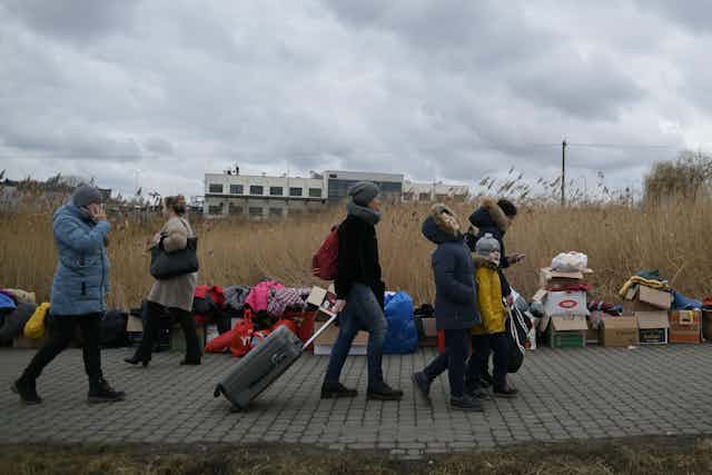 People walking with suitcases over the border into Poland.