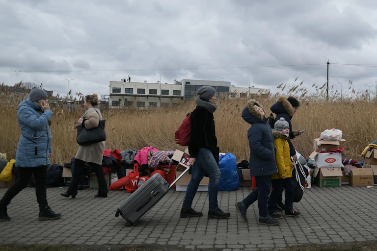 People walking with suitcases over the border into Poland.