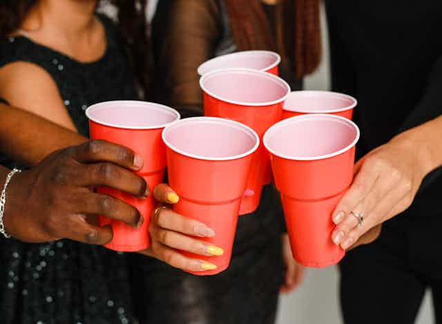 A group of people clink red plastic cups. 