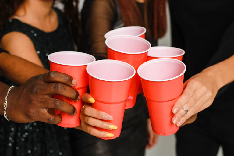A group of people clink red plastic cups.