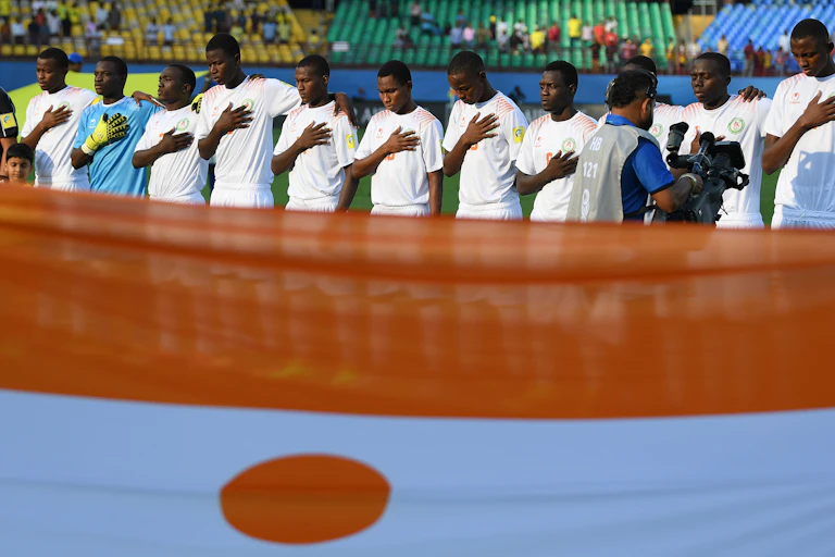 Des garçons debout en rang derrière le drapeau du Niger