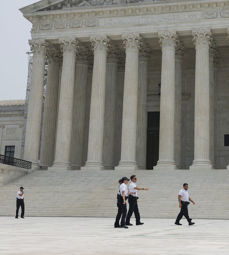 Police officers patrolling the front of the Supreme Court building