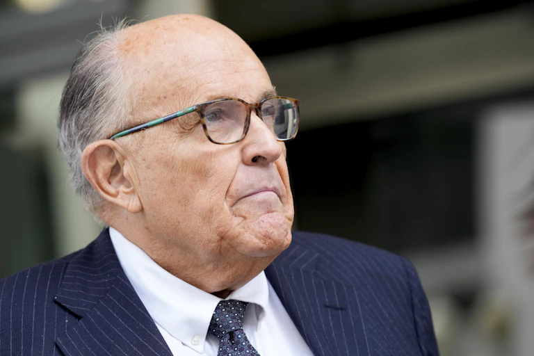 A man wears glasses and a coat and tie.
