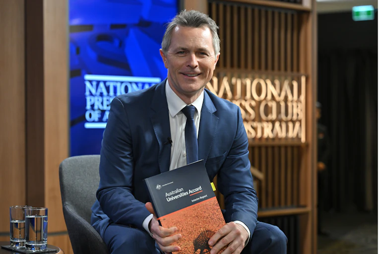 Education Minister Jason Clare holds a copy of the Universities Accord interim review.