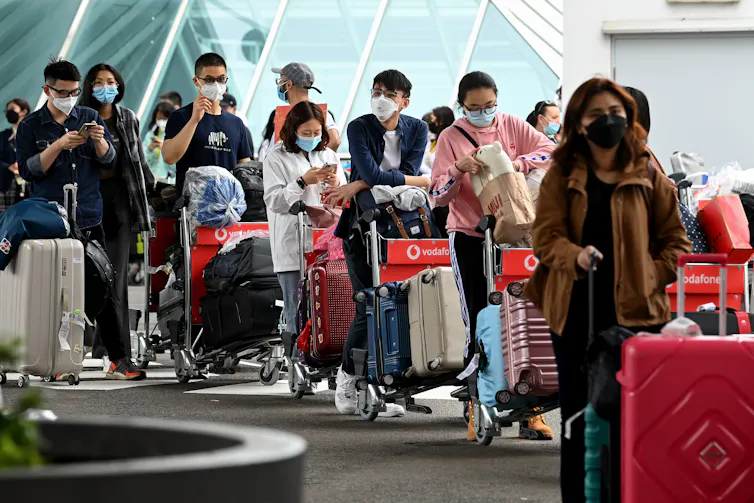 International students queue with bags as they arrive at Sydney airport in December 2021.