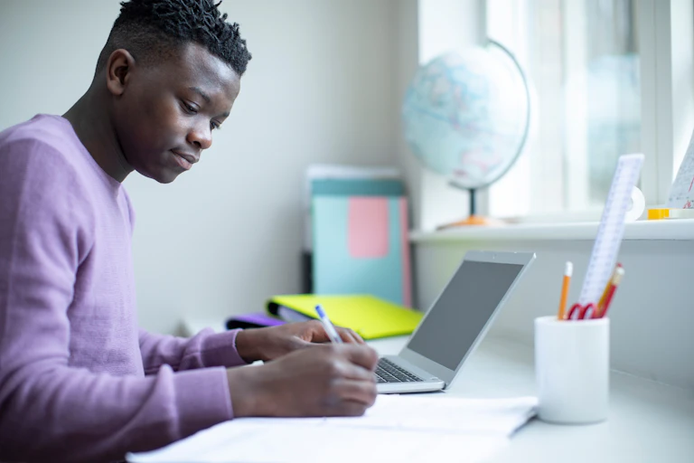 Teenage boy doing homework with laptop open