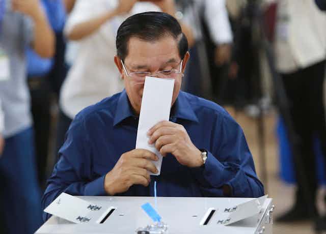 Cambodian prime minister Hun Sen kisses his ballot paper before voting, July 2023.
