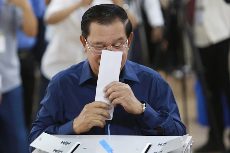 Cambodian prime minister Hun Sen kisses his ballot paper before voting, July 2023.