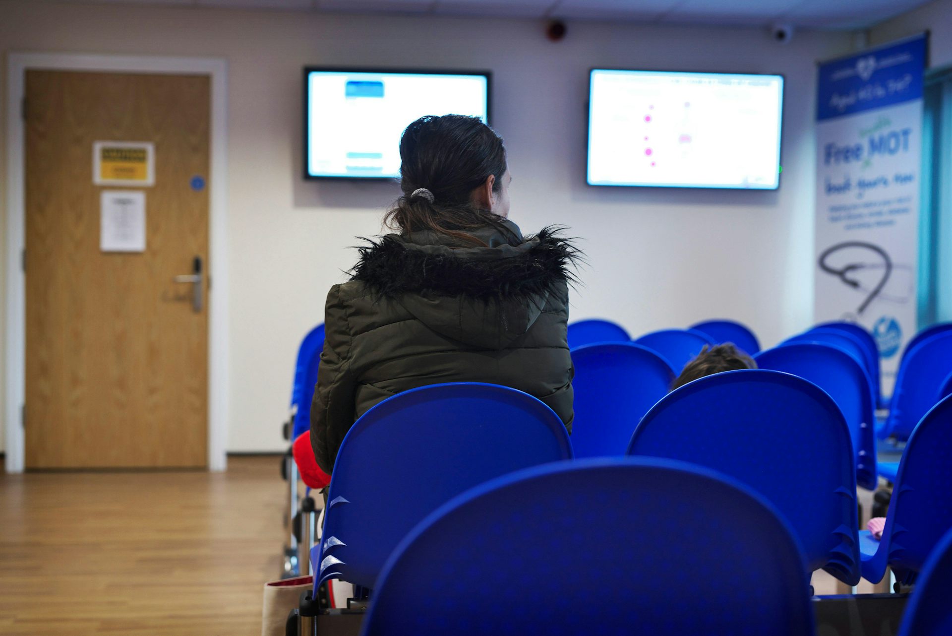 Parent and child in otherwise empty GP surgery waiting room