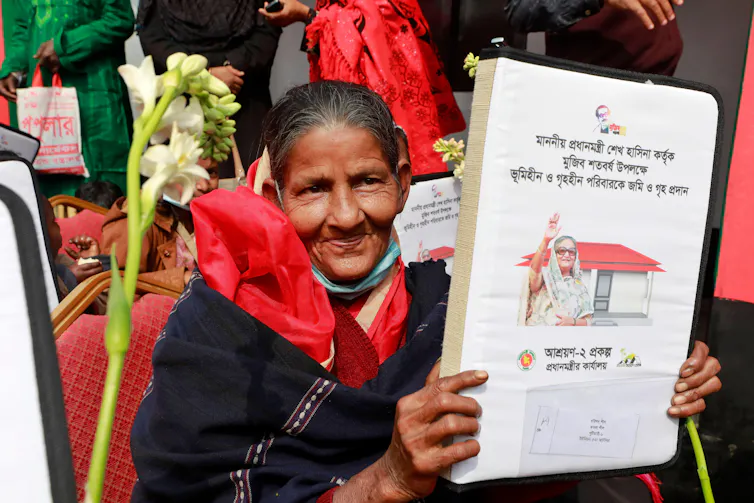 A woman in red and black with a large folder of documents.