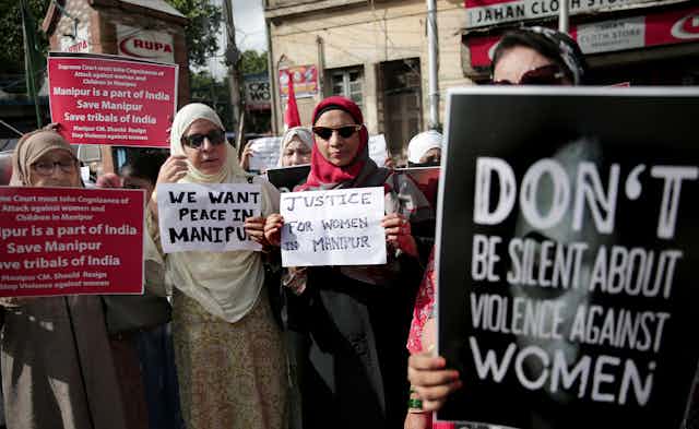 A group of Muslim women hold up placards in protest at sexual violence.