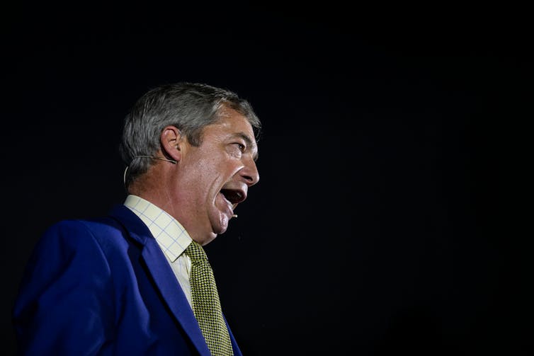 Photo of Nigel Farage speaking at an event, against a dark background