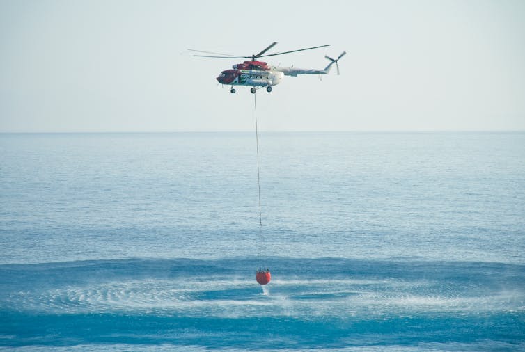 Firefighting helicopter drawing water from the sea.