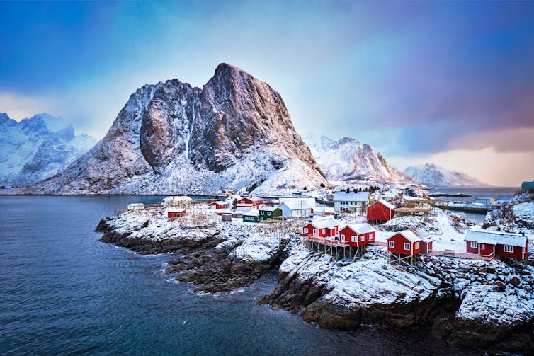 Ciudad noruega junto al mar, montaña nevada al fondo