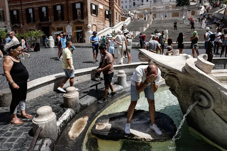 People cool off around a water fountain.