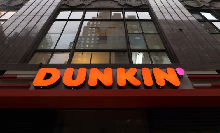 The orange Dunkin' logo see on a big brown building.