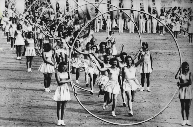 An archival photograph of athletes jumping through hoops.