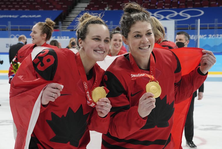 Two women hockey players pose for a photo with their gold medals